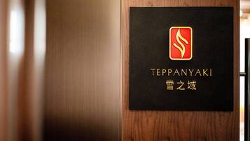 A black sign with gold lettering and a red logo on a wooden door.