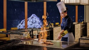 A chef cooking on a grill with a mountain backdrop. - Shanghai Snow World Hotel, Vignette Collection by IHG (Shanghai)