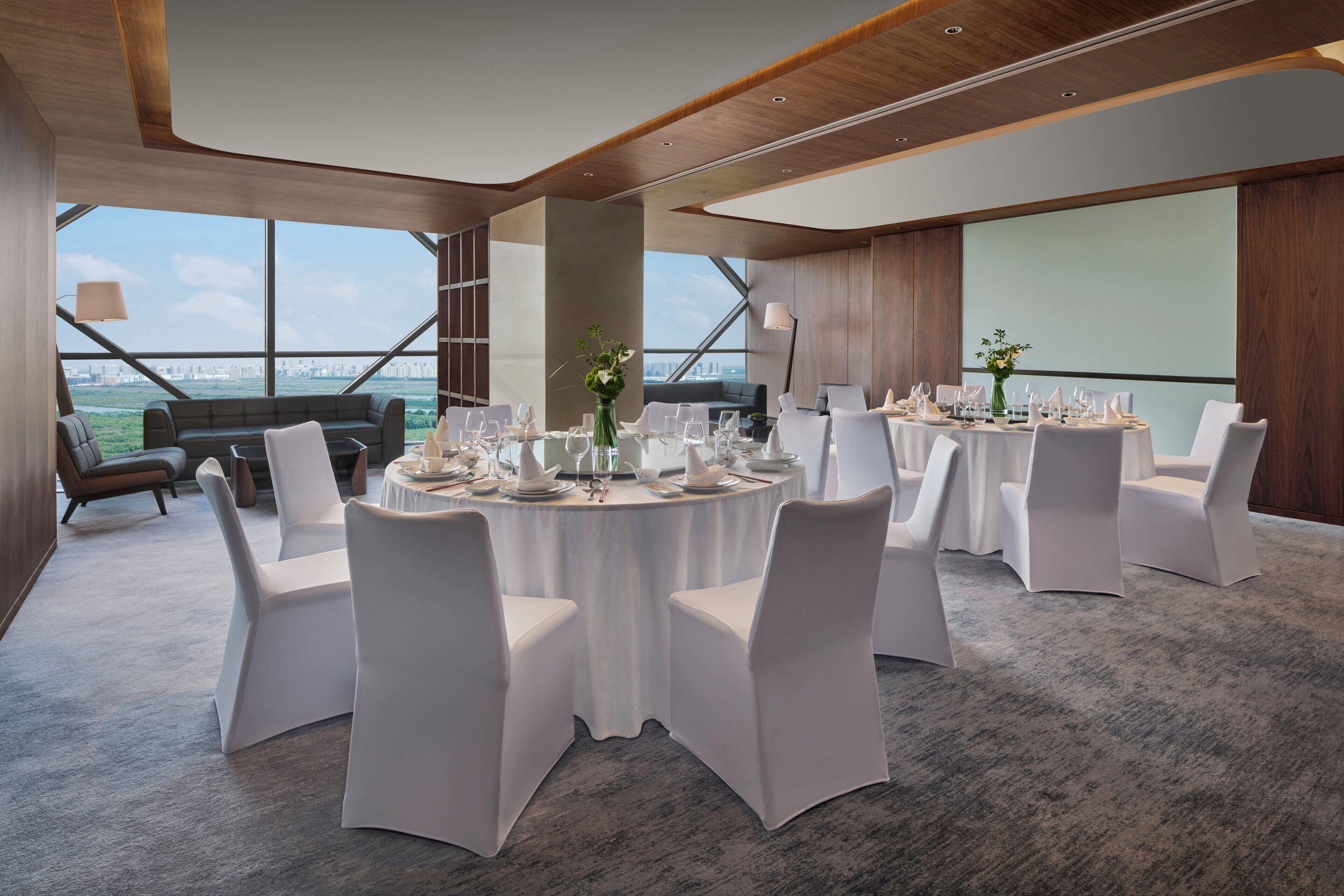 Un espace repas moderne avec des tables rondes, des chaises blanches et une vue sur la ville.