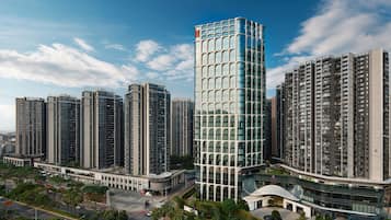 Un ensemble immobilier composé d’immeubles de grande hauteur, comprenant plusieurs tours résidentielles, une structure centrale en verre et des espaces verts environnants.