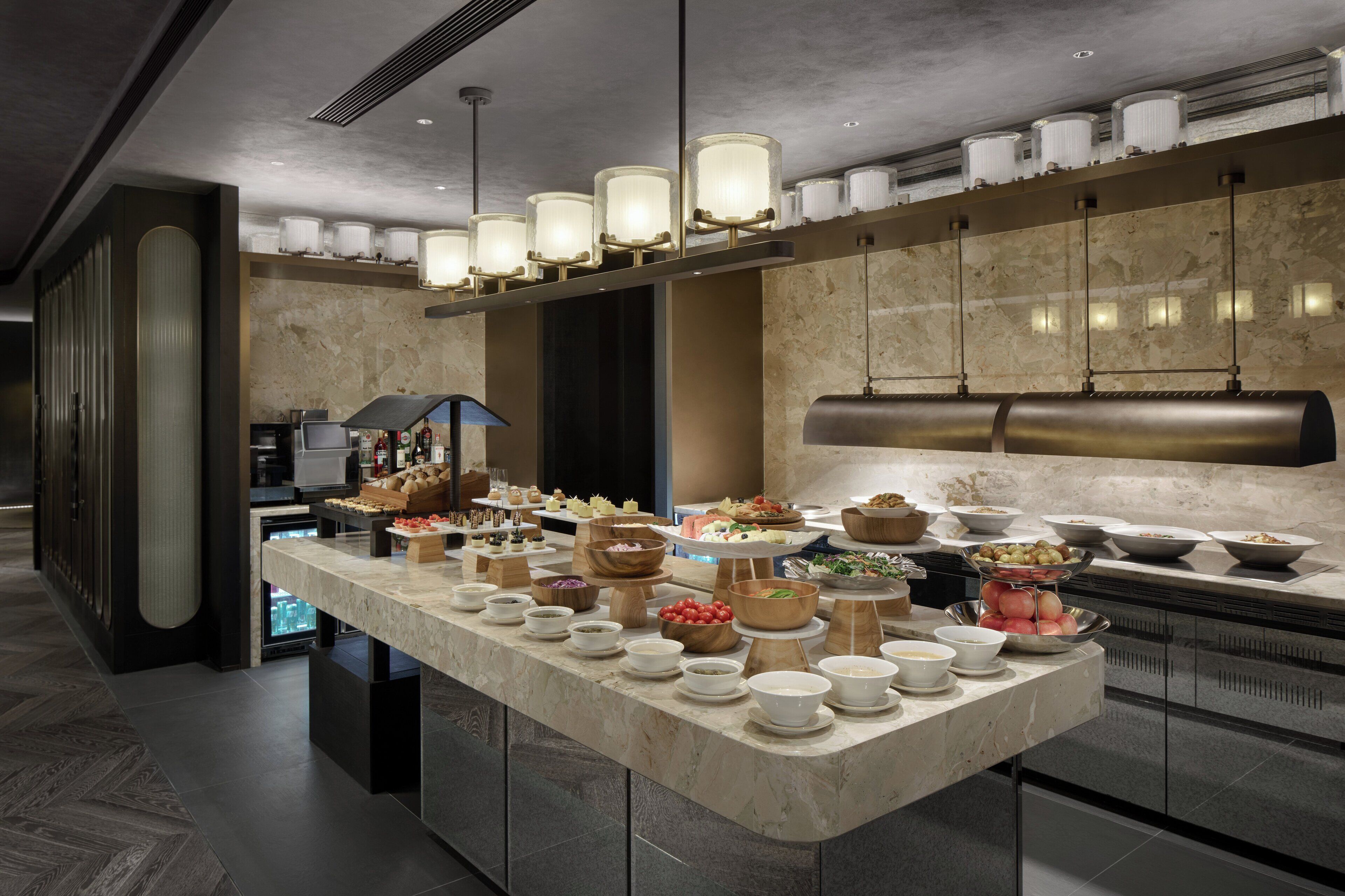 A buffet setup with various food items and a modern kitchen in the background.