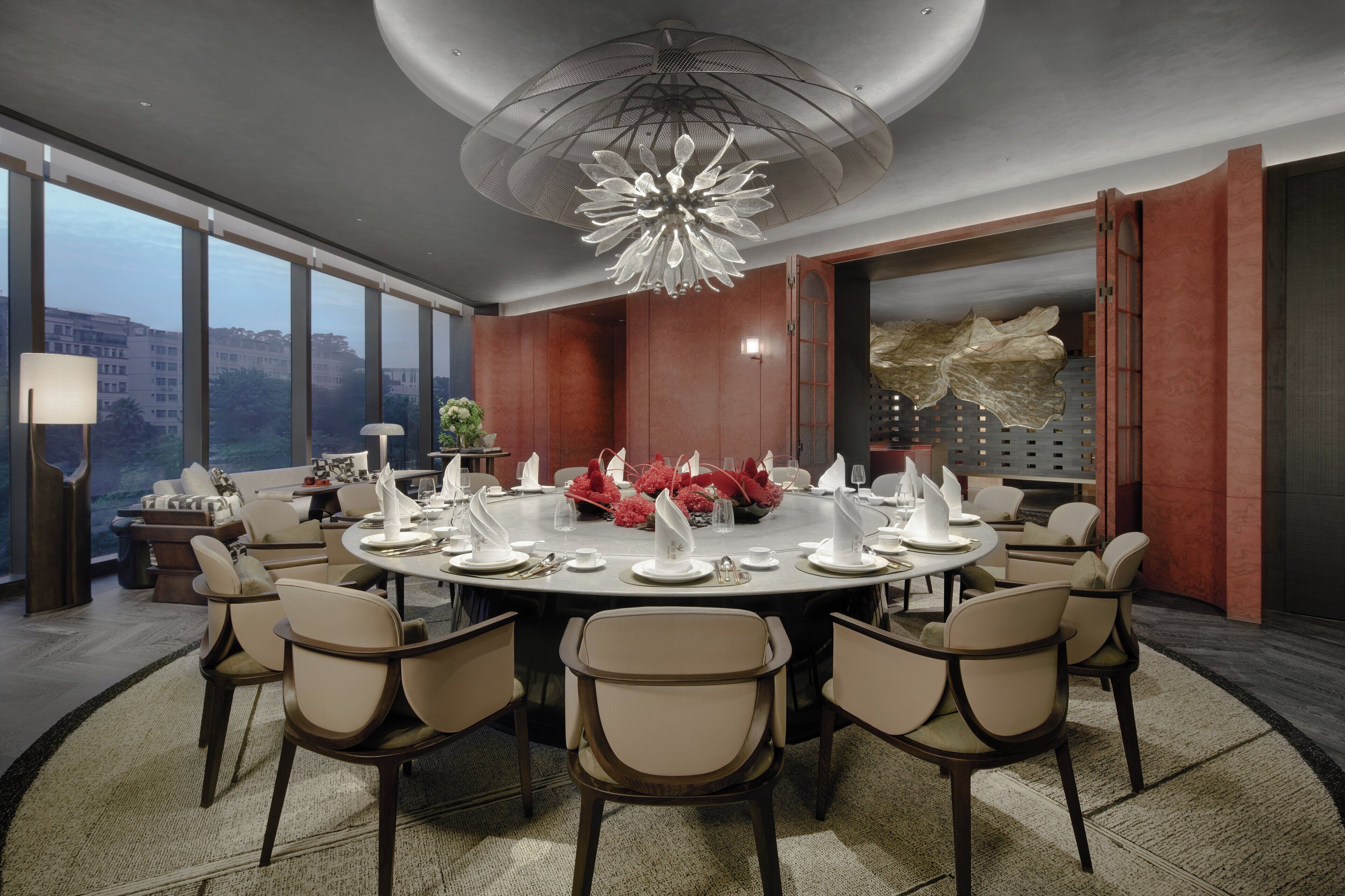 Une salle à manger moderne avec une table ronde dressée pour six personnes, entourée de six chaises.
