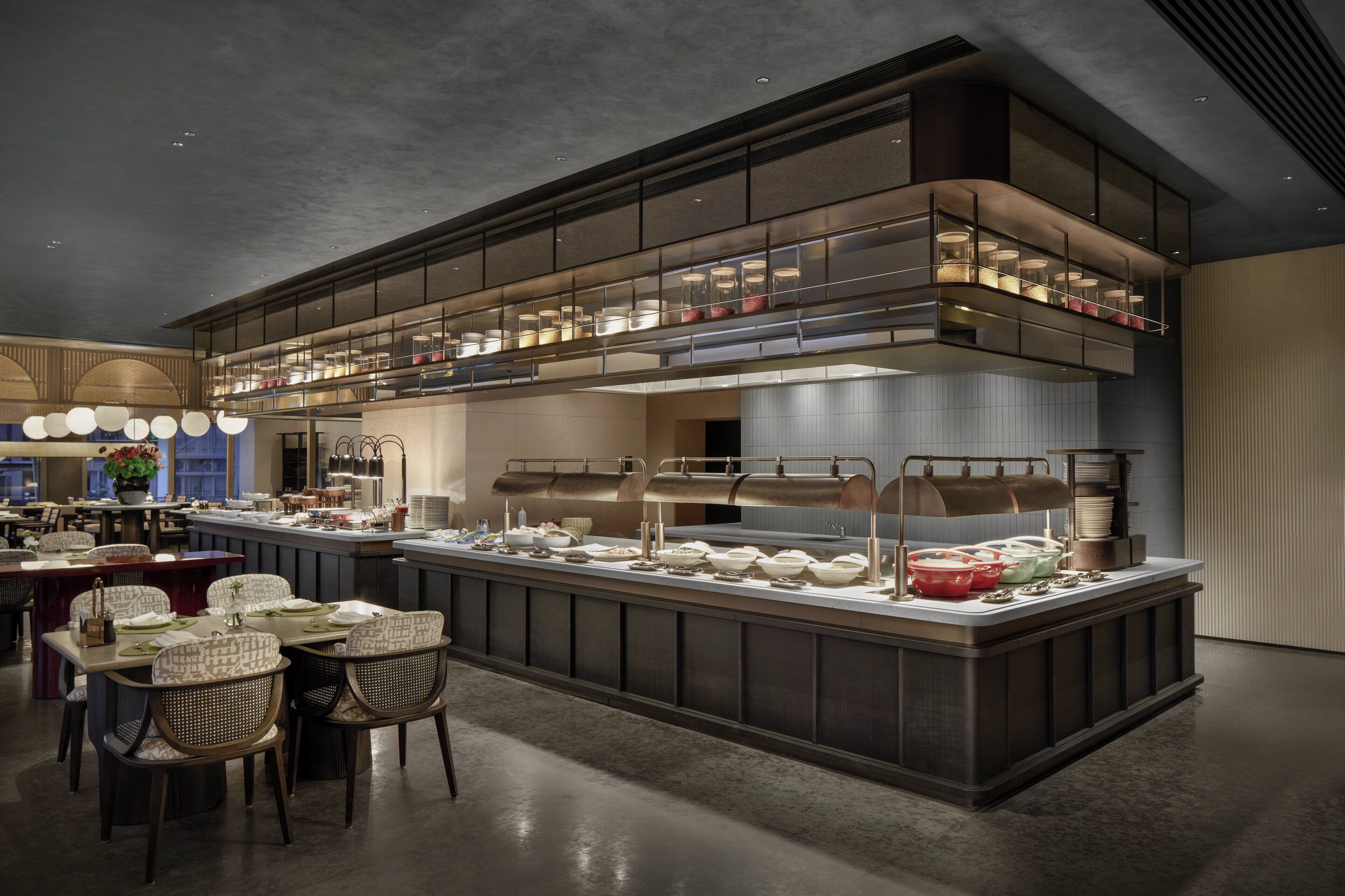A modern restaurant with a central island, multiple dining tables, and a mezzanine level with seating.