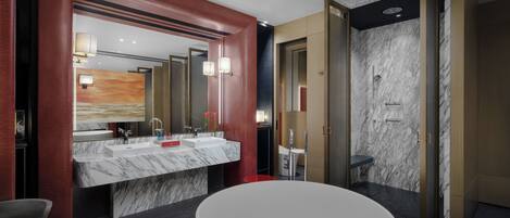 Une salle de bain moderne dotée d’un grand lavabo en marbre, d’une baignoire sur pieds et d’un espace douche aux murs en marbre.