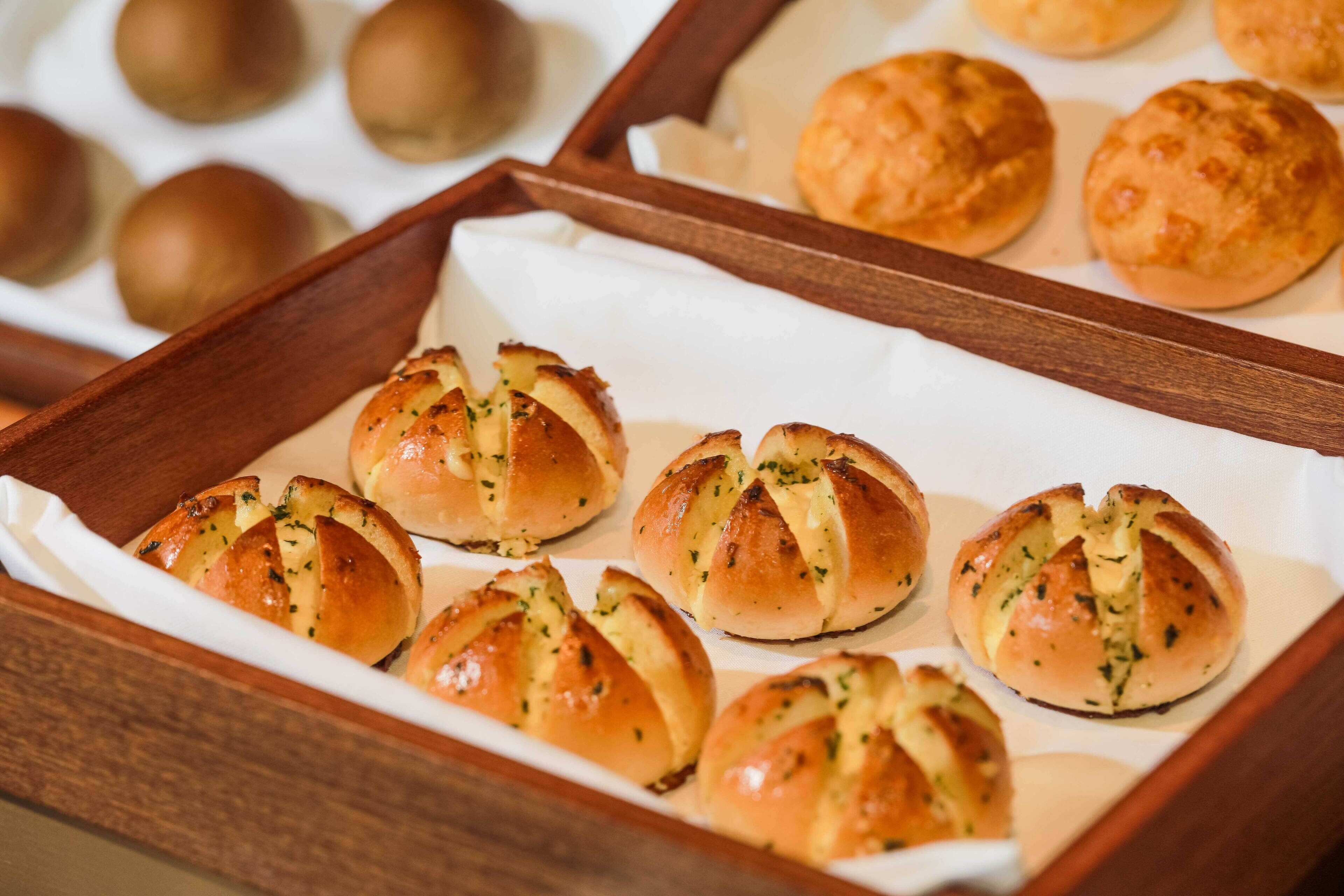 A tray of freshly baked bread rolls with herbs and melted cheese.