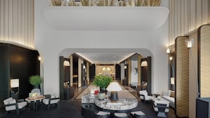 Un hall d’hôtel moderne doté d’un espace salon central, d’un comptoir d’accueil et d’une composition florale décorative.