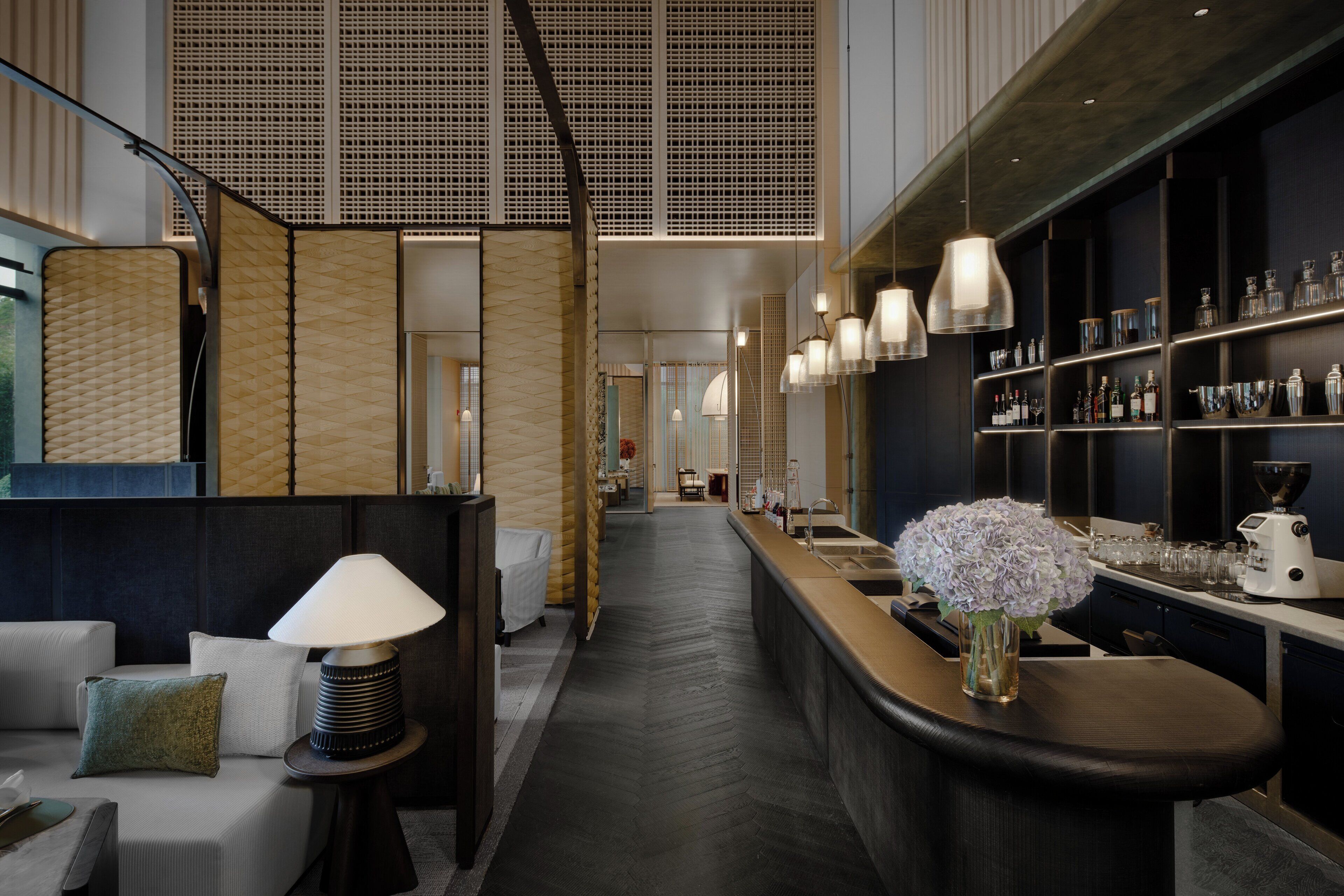 A modern hotel lobby with a reception desk, seating area, and a bar.