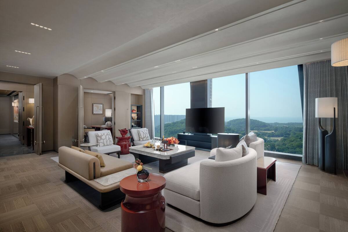 A modern living room with a large flat-screen TV, comfortable seating, and a view of the outdoors.