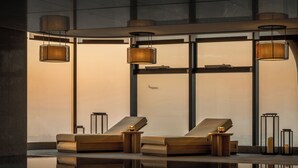 Un espace spa moderne comprenant deux chaises longues, un bassin décoratif et un éclairage d’ambiance.