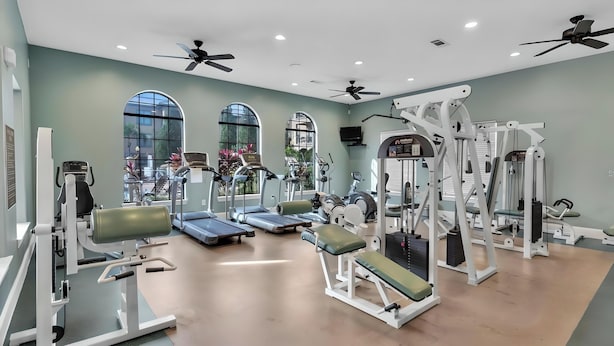 Een sportschool met loopbanden, krachtapparaten en plafondventilatoren.