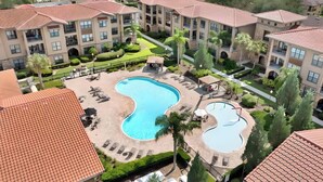 Een resort met een centraal gelegen zwembad, ligbedden en een aangelegde tuin.