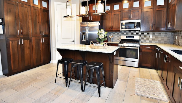 A modern kitchen with dark wood cabinets, stainless steel appliances, and a central island with stools. - Entrada at Moab 424 and 428 (Moab)
