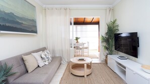 A modern living room with a sofa, a round coffee table, a flat-screen TV, and a dining area with a table and chairs. - Tranquil Coastal Escape, Porís de Abona (Porís de Abona)