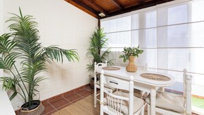 A corner room with a white table and chairs, potted plants, and a view through large windows. - Tranquil Coastal Escape, Porís de Abona (Porís de Abona)