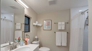 A modern bathroom with a sink, toilet, and shower. There are multiple towels and a framed picture on the wall. - Casita Sam Hughes/University King bed (Tucson)