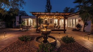 A well-lit outdoor patio area with a central fountain, surrounded by seating and potted plants. - Pool & Hot tub! Sam Hughes University Lux!Walkable (Tucson)
