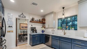 A modern kitchen with dark blue cabinets, a white countertop, and a window with a view of trees. - Pool & Hot tub! Sam Hughes University Lux!Walkable (Tucson)