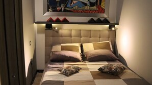 Una camera da letto con un letto, cuscini e un grande quadro astratto sopra il letto.