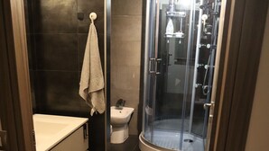 Un bagno con doccia vetrata, un water e un lavandino.