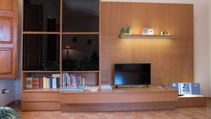 Un salon moderne doté d’un meuble de rangement intégré pour les appareils multimédias, de bibliothèques et d’un téléviseur à écran plat.