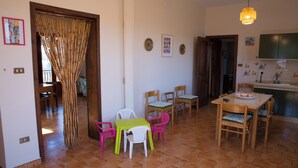 Un coin repas avec une table et des chaises, une cuisine en arrière-plan et un rideau en bambou.
