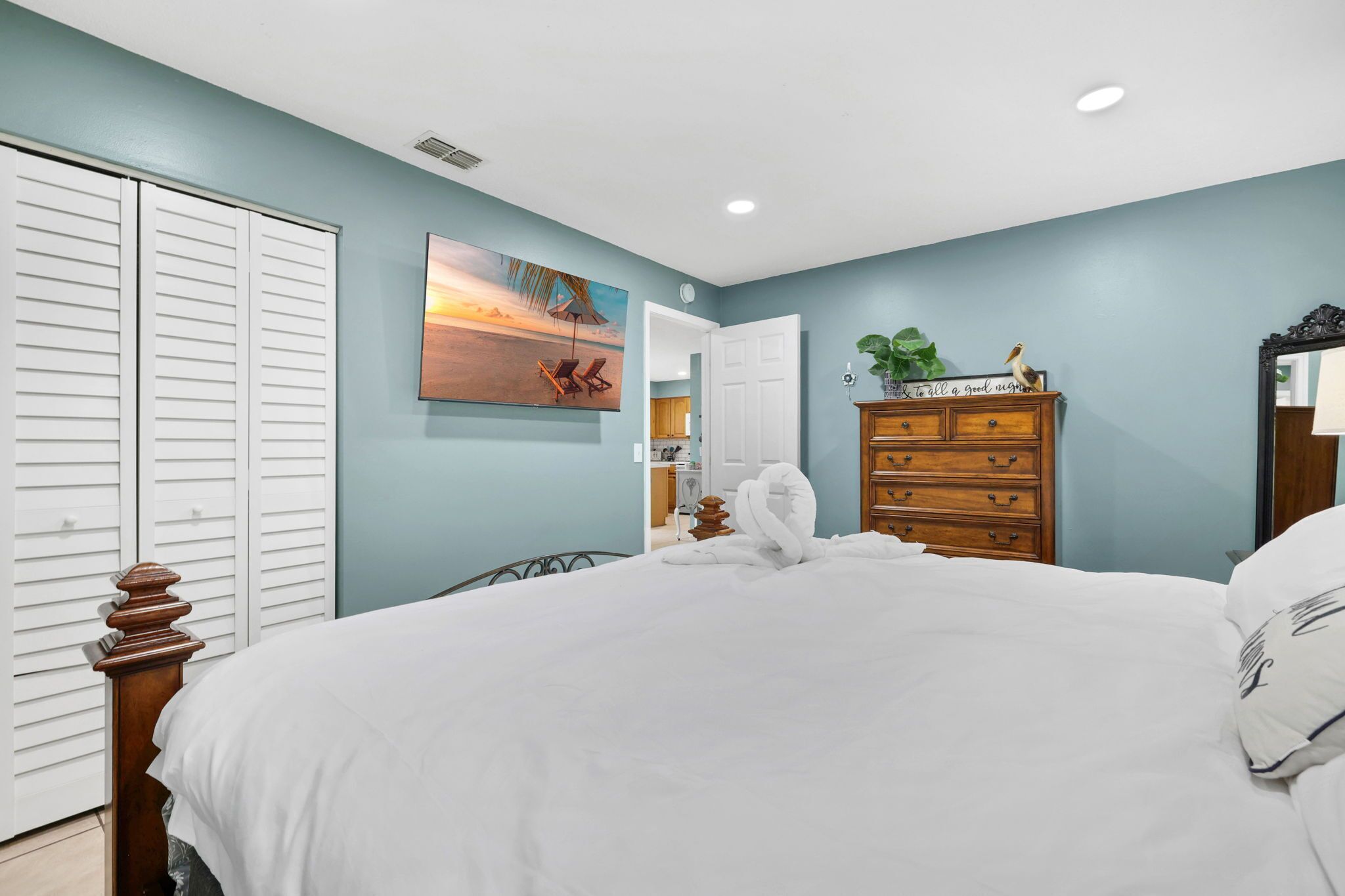 A bedroom with a bed, a dresser, a painting, and a closet.