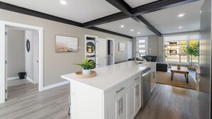 Een moderne keuken met witte kastjes, een groot eiland en uitzicht op de omgeving.