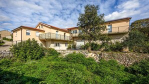 A two-story building with a balcony, surrounded by greenery and a stone wall. - Pet friendly apartment in Imotski with WiFi (Imotski)
