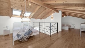A spacious attic bedroom with a wooden ceiling, a hammock bed, a metal bed frame, and a skylight. - Amazing home in Funtana (Funtana)