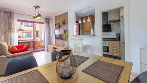 A modern apartment with a dining area, kitchen, and a balcony with a view.