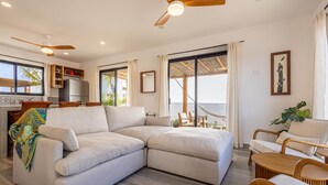 A modern living room with a sectional sofa, a dining area, and a kitchen. - El Corazón Contento | Cerritos Beach (La Paz)