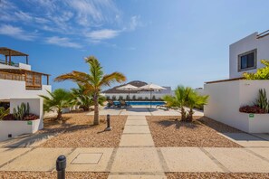 Een resort met een zwembad, palmbomen en uitzicht op een berg.