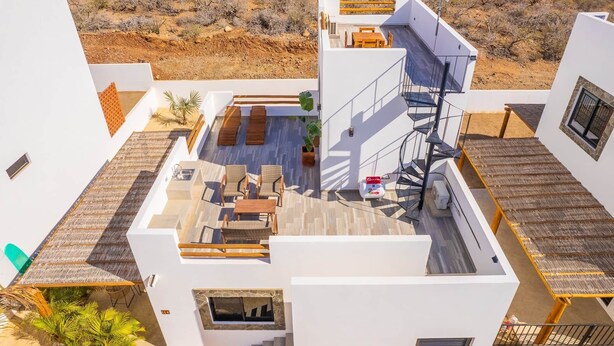A modern building with a rooftop patio, outdoor seating, and a staircase. - El Corazón Contento | Cerritos Beach (La Paz)