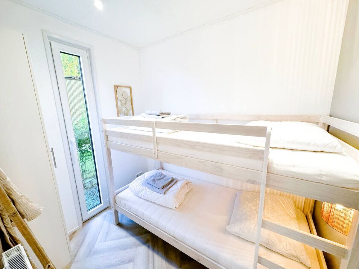 Een slaapkamer met een stapelbed en een schuifdeur naar een balkon.