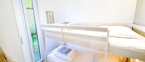 Een slaapkamer met een stapelbed en een schuifdeur naar een balkon.