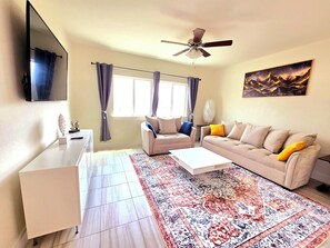 A living room with a sofa, coffee table, and a large rug.