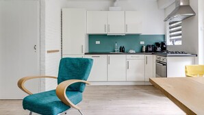 A modern kitchen with white cabinets, a teal backsplash, and a wooden dining table.