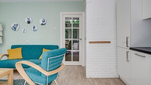 A modern living space with a teal sofa, wooden chair, and white brick wall.