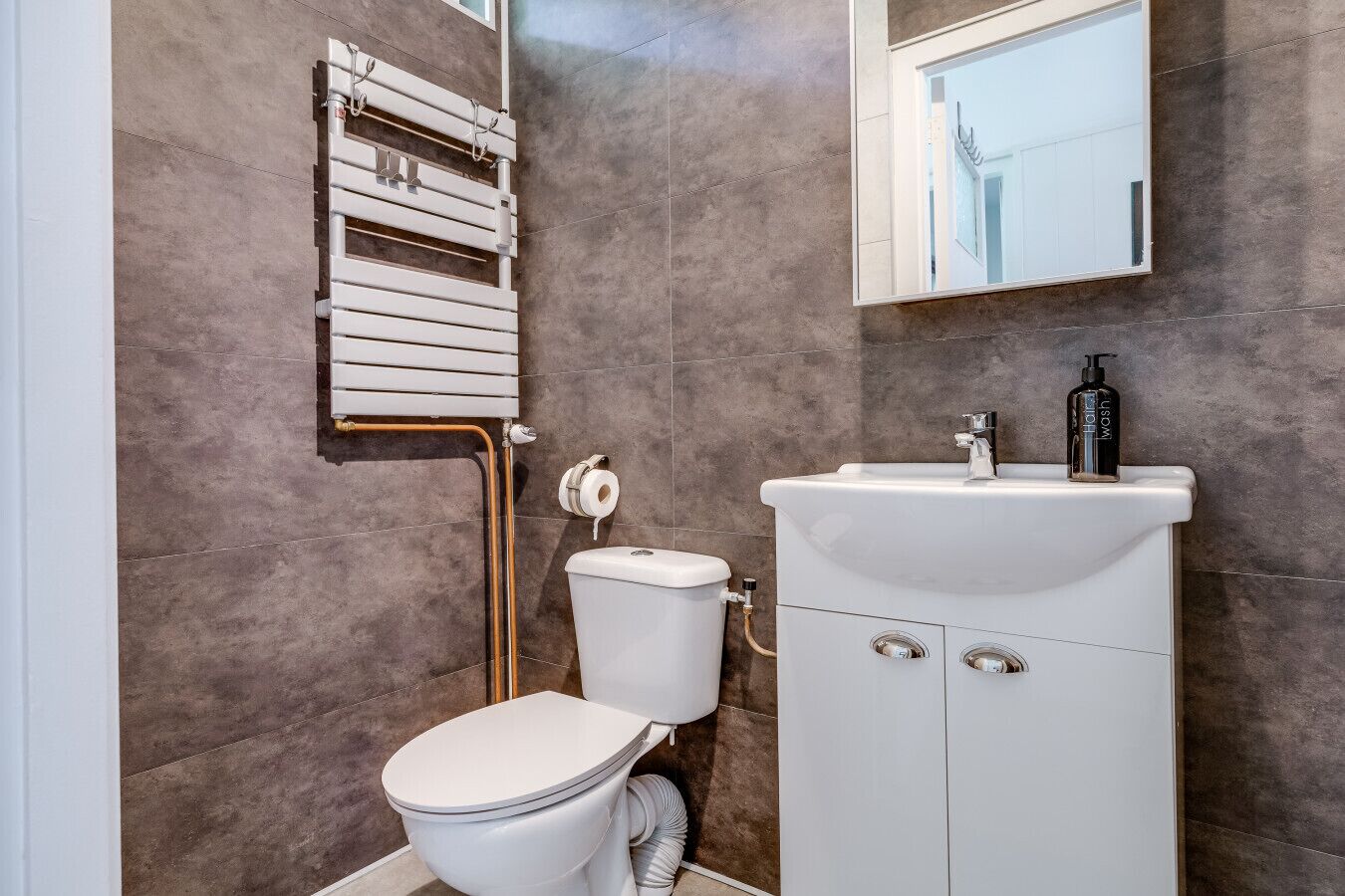 Une salle de bain moderne équipée de toilettes, d’un lavabo et d’un porte-serviettes.