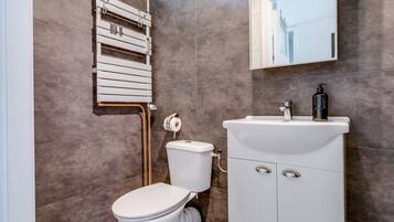 Une salle de bain moderne équipée de toilettes, d’un lavabo et d’un porte-serviettes.