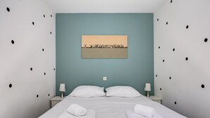 Een hotelkamer met een bed, twee kussens, twee nachtkastjes met lampen en een schilderij aan de muur.