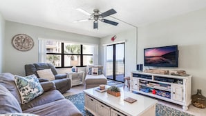 Ein Wohnzimmer mit Sofa, Couchtisch, Fernseher und einem Balkon mit Aussicht.