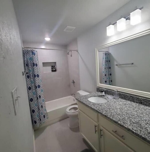A bathroom with a shower, toilet, and sink.