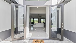 Une entrée moderne avec des portes vitrées donnant sur un espace de vie comprenant un canapé et une table à manger.