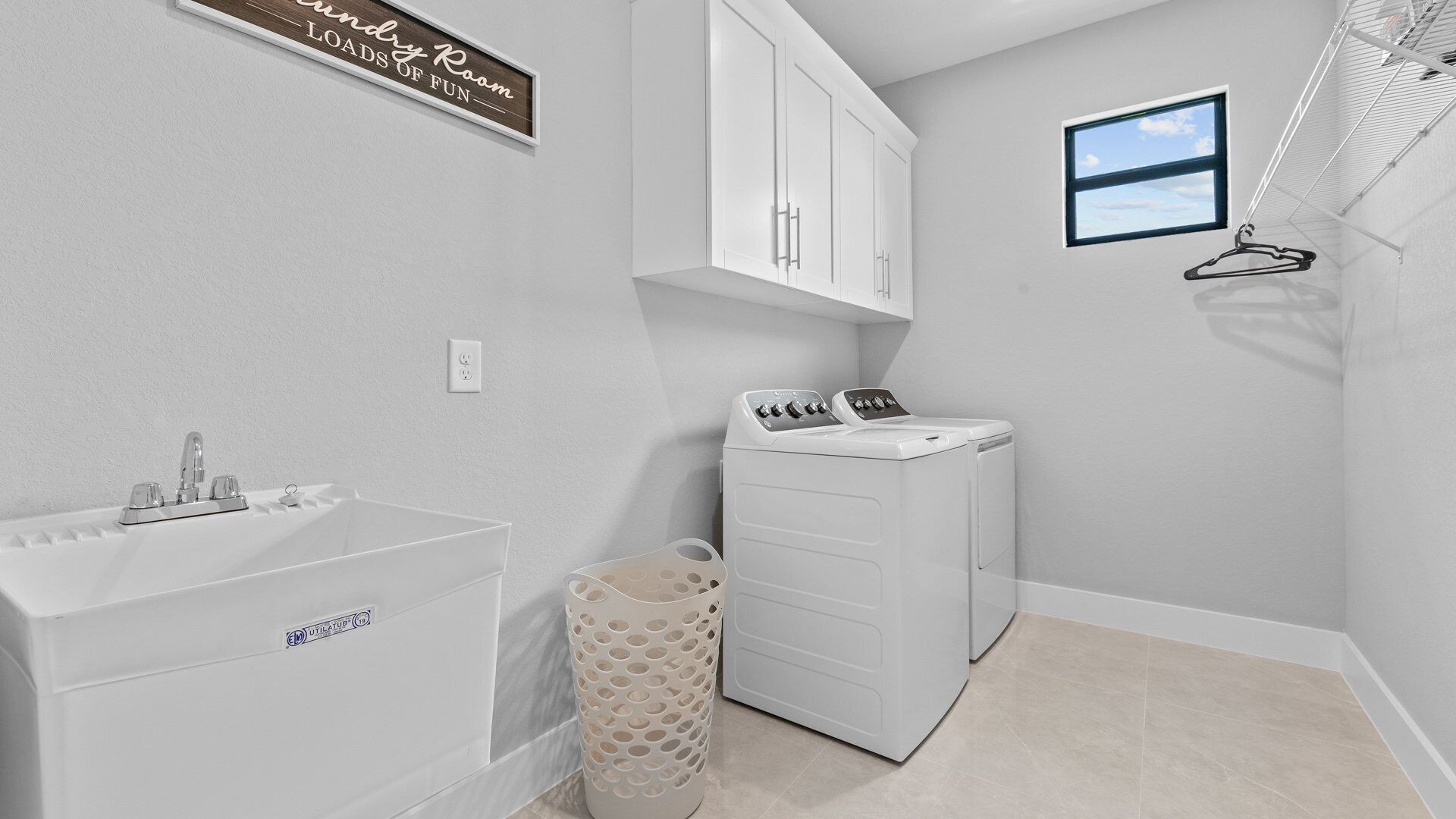 A laundry room with a sink, a washing machine, and a drying rack.