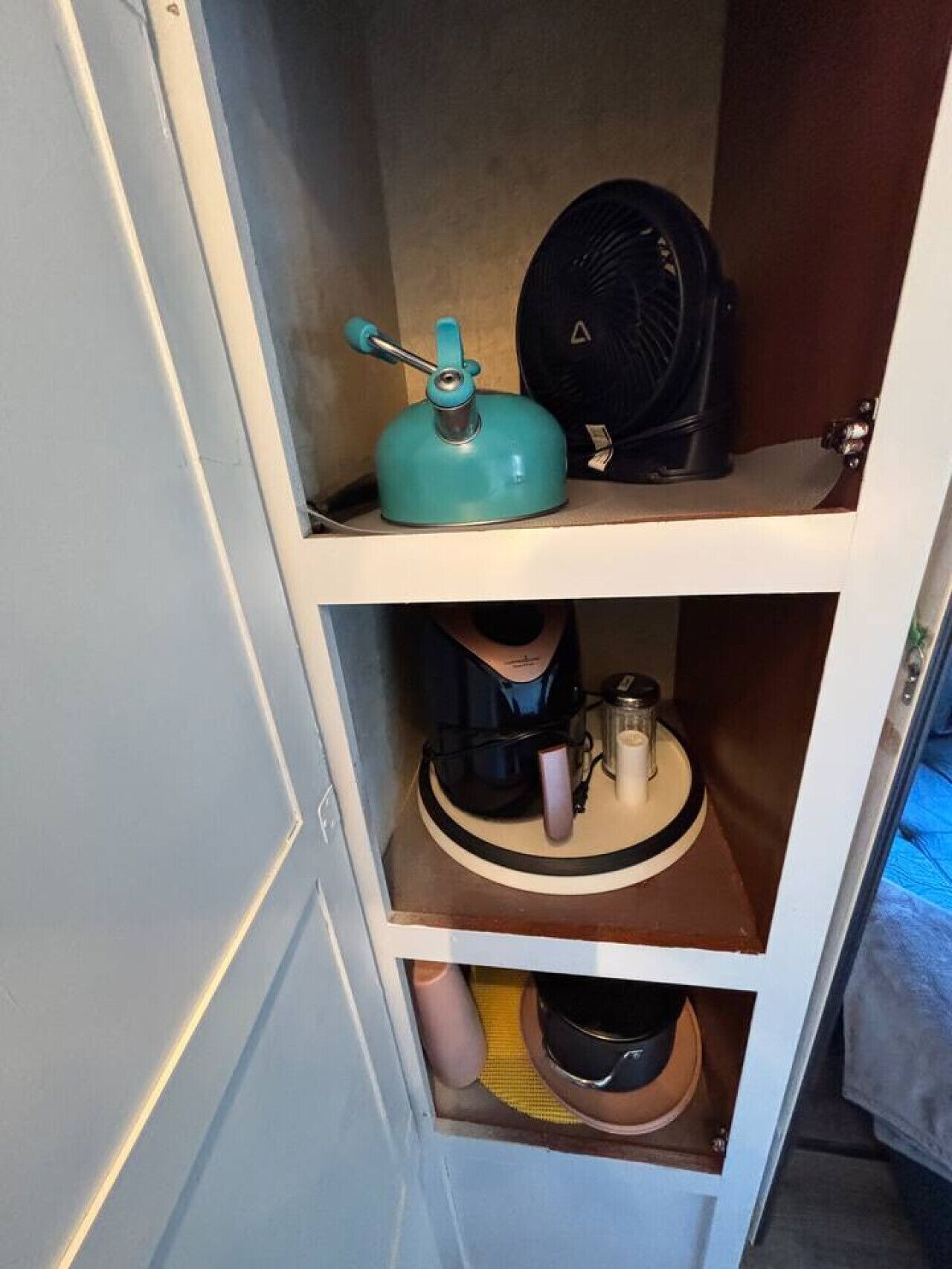 Eine Küche mit einem türkisfarbenen Wasserkocher, einem schwarzen Gerät und einer Kaffeemaschine auf der Arbeitsfläche.