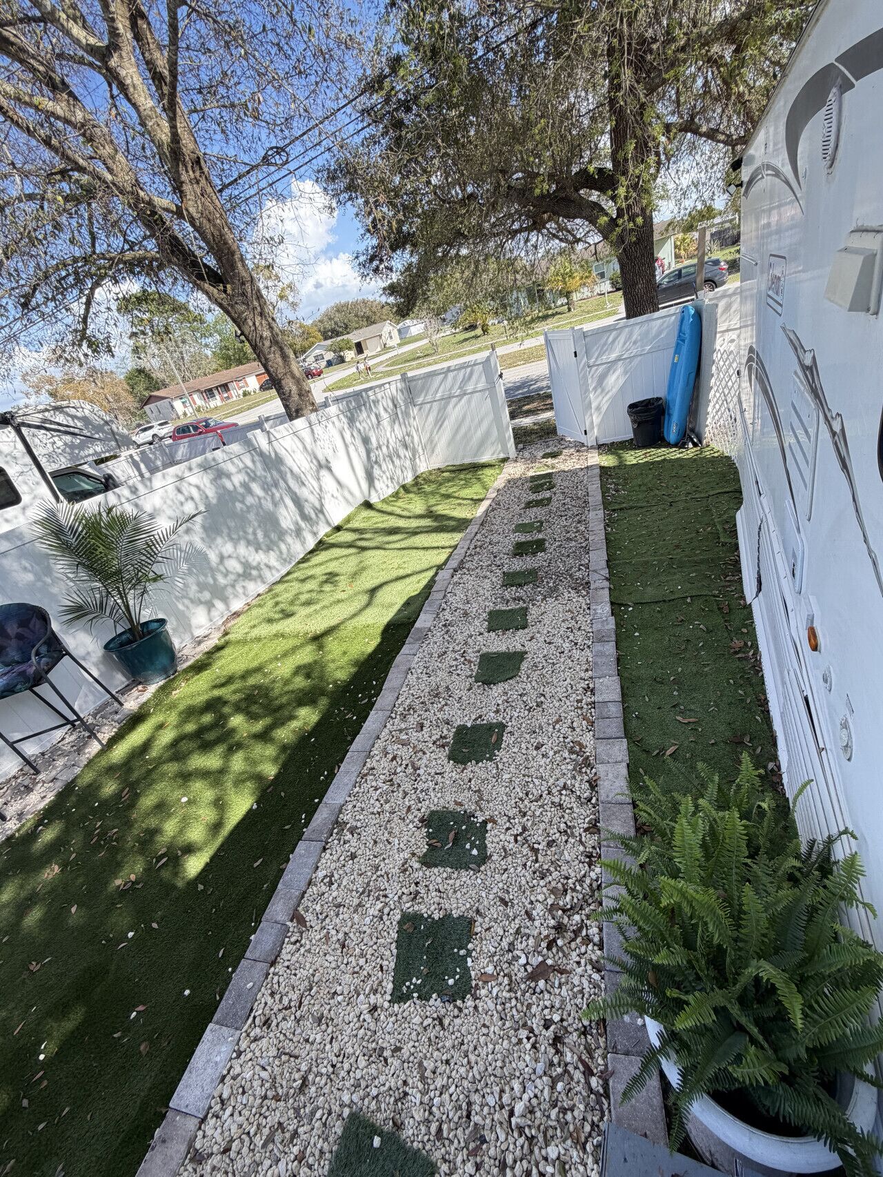 A compact outdoor area with artificial grass, a gravel path, and a white fence.