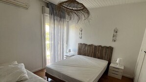 A bedroom with a large bed, a smaller bed, a nightstand, a hanging light fixture, and a window with curtains. - Villa T4 type canétoise air-conditioned and near beach - 6ILEF56 (CANET PLAGE)