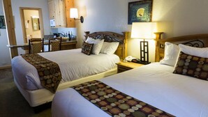 Et hotelværelse med to senge, et lille tekøkken, et spiseområde og et badeværelse.