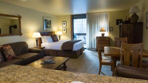 A hotel room with a bed, a sofa, a dining table, and a chair. There are lamps on the bedside table and a window with curtains. - Cozy Studio Condo with Fully Equipped Kitchen (Truckee)